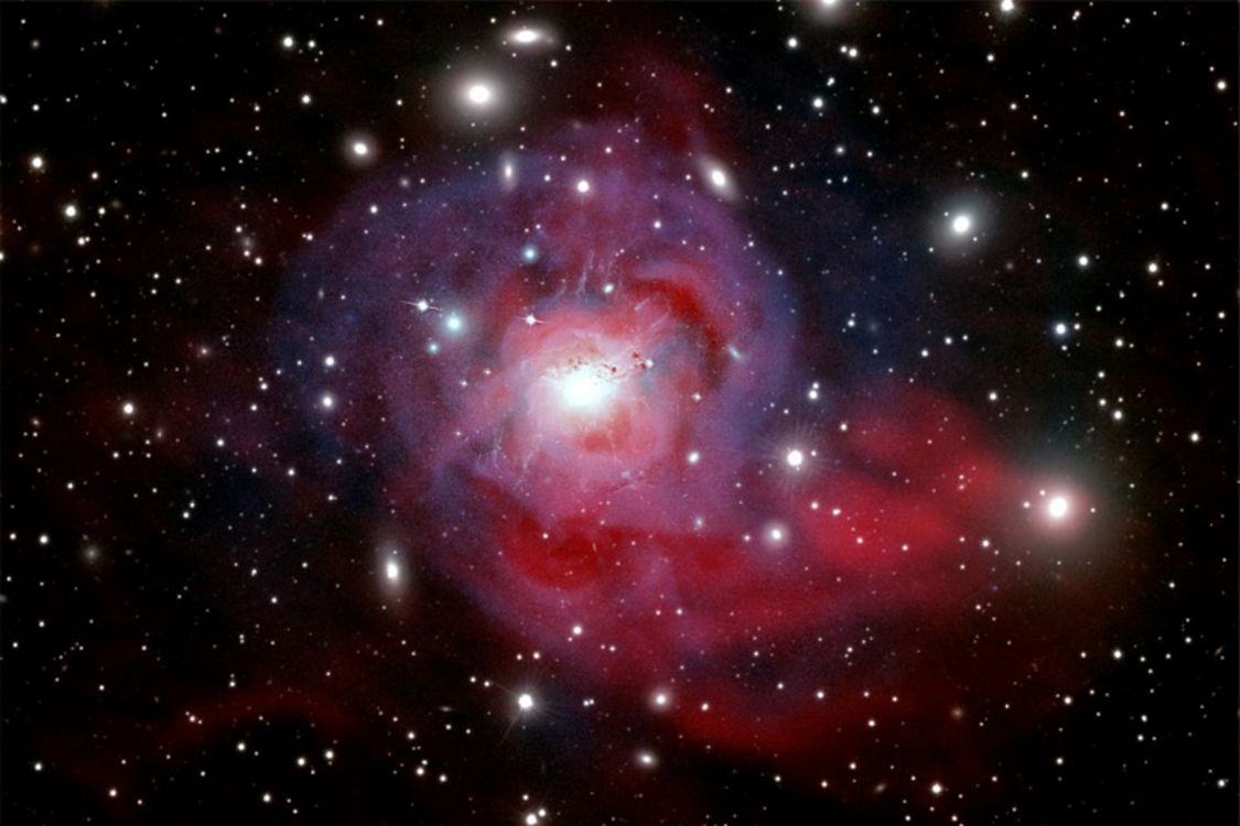 Au centre de l’amas de Persée trône la spectaculaire galaxie NGC 1275, où se cache un trou noir supermassif responsable de puissants jets de particules (en rose). Éjectées bien au-delà de la galaxie, ces particules entretiendraient la température incroyablement élevée (60 millions de degrés Celsius) des gaz qui s’étendent entre les galaxies (en bleu).